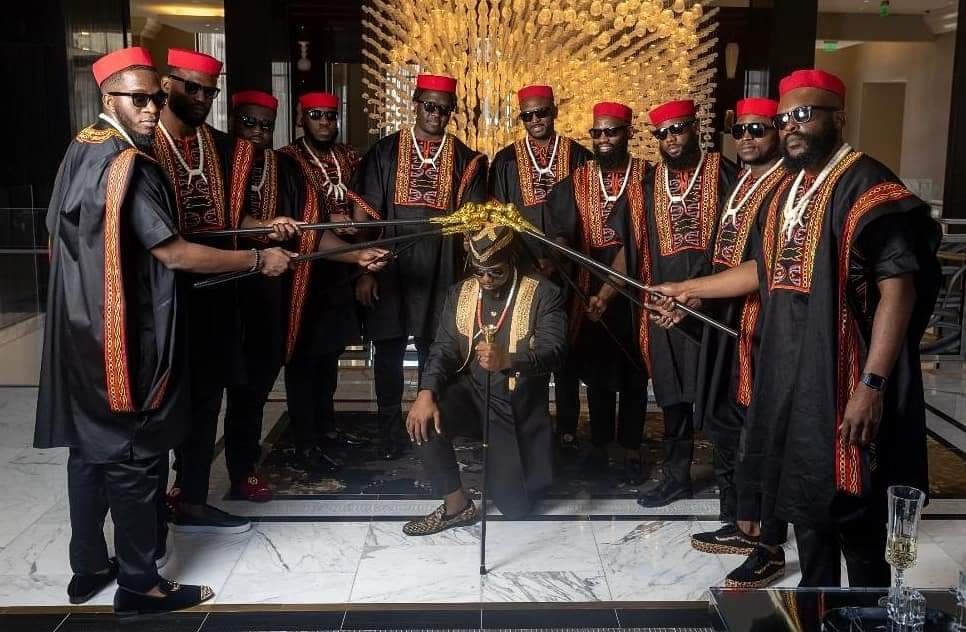 Groomsmen in black Toghu embroidered outfits with red caps holding swords